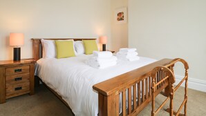 A neatly made bed with white linens, two bedside lamps, and a wooden headboard. - Shields (Keswick)