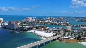 A coastal cityscape with a prominent bridge, beachfront properties, and a marina.