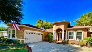 A two-story house with a garage, a covered porch, and a well-maintained lawn.