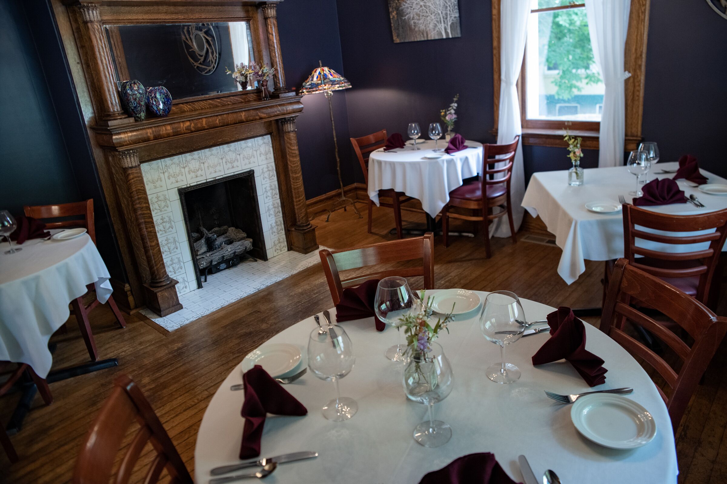 A dining area with round tables, chairs, and a fireplace.