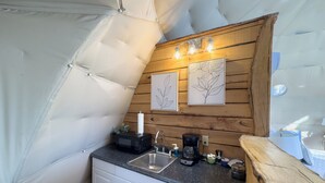 Une cuisine compacte équipée d’un évier, d’un four à micro-ondes, d’une machine à café et agrémentée de touches de bois.