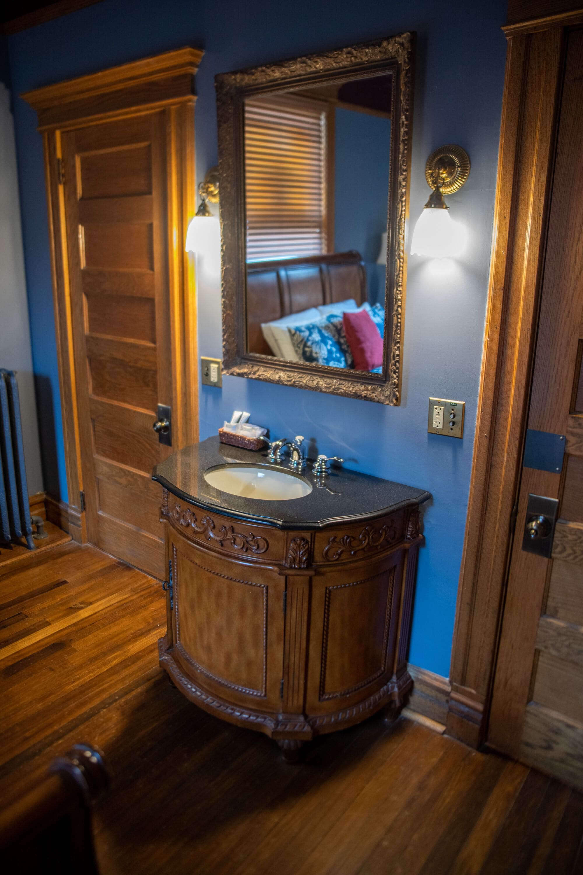 A bathroom with a wooden vanity, a large mirror, and a sink.