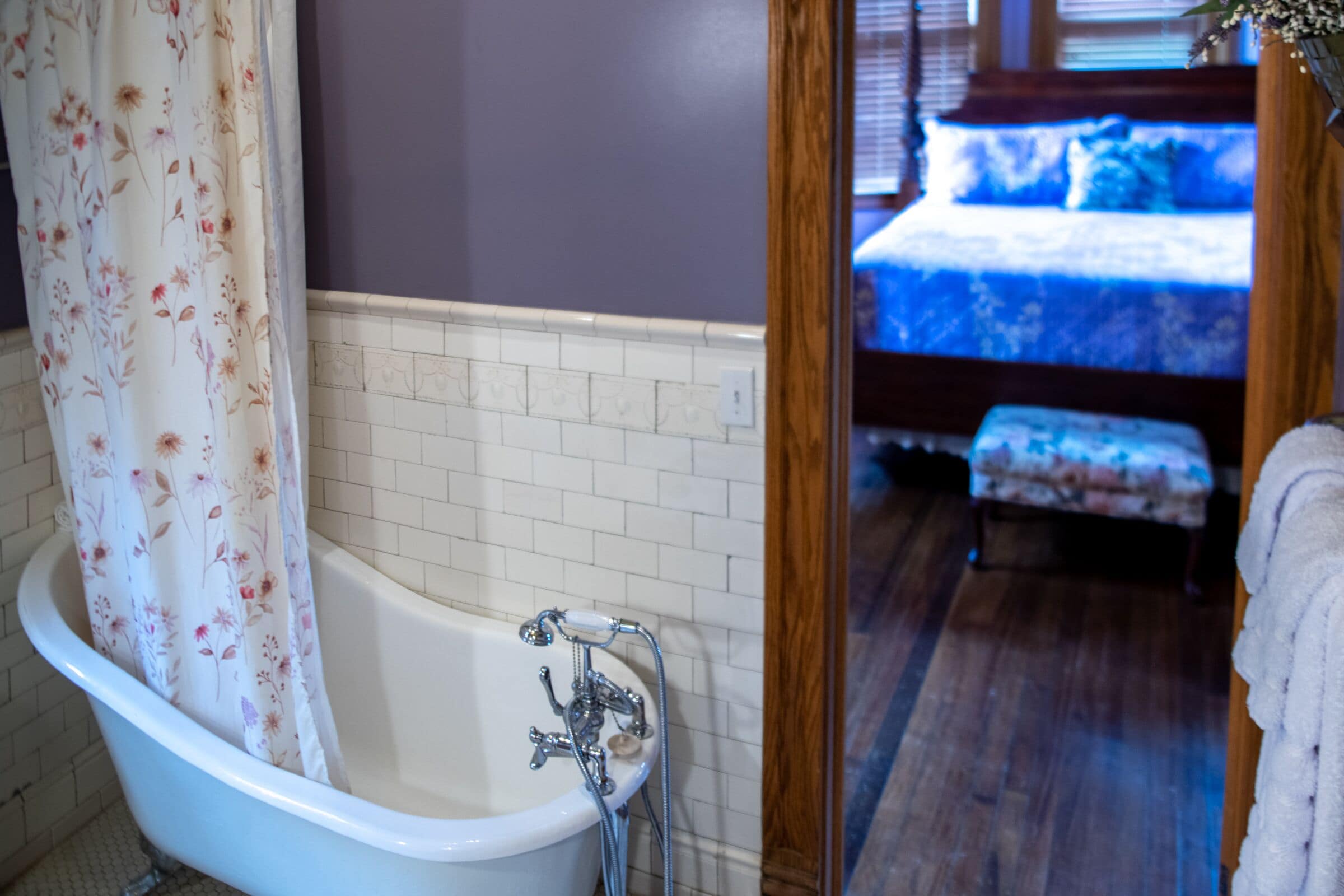 Un baño con una bañera independiente, ducha y una cama visible en la habitación contigua.