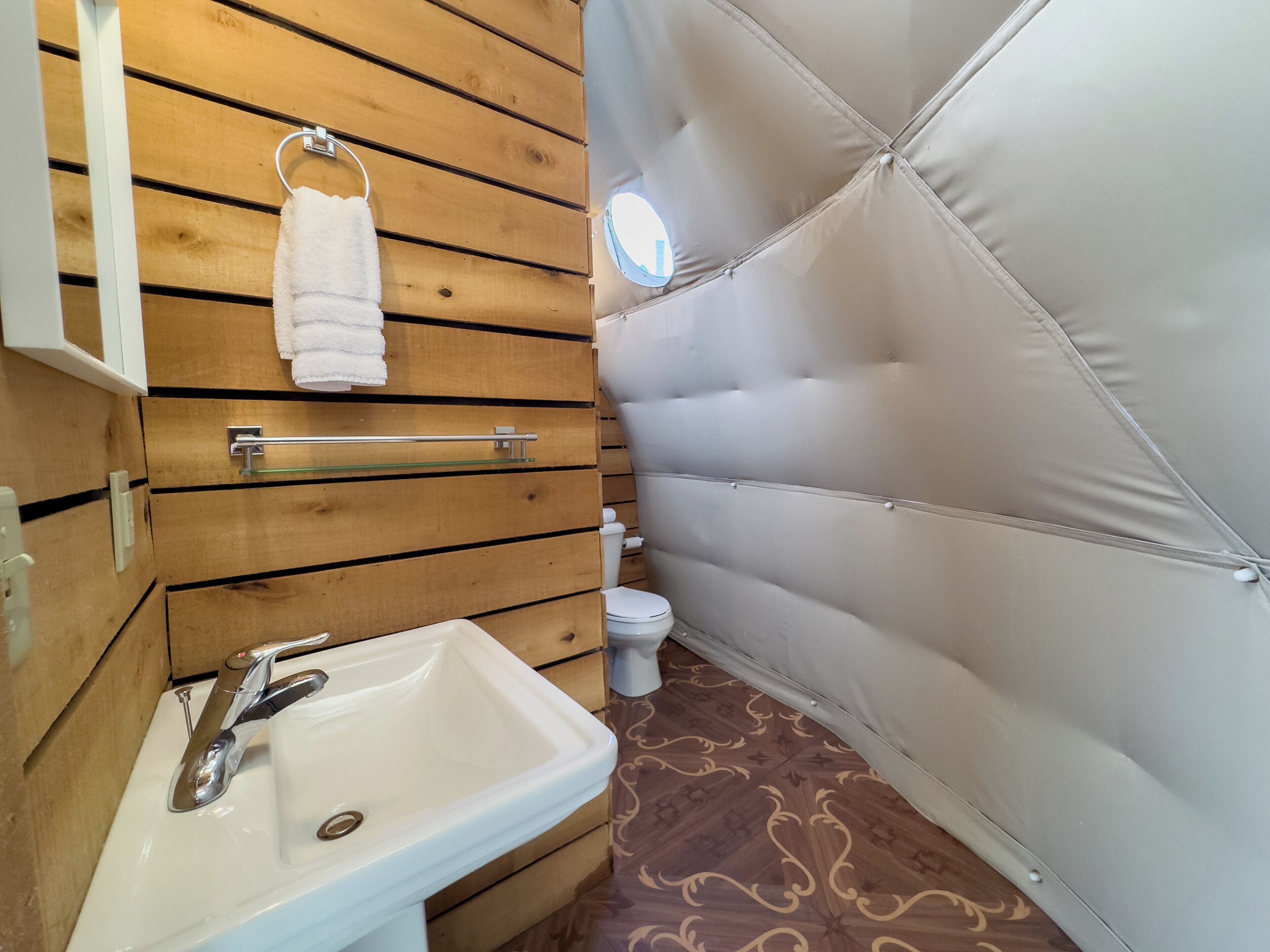 A bathroom with a wooden vanity, a white sink, and a toilet.