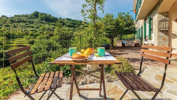Un espace extérieur aménagé pour prendre les repas, avec une table dressée pour le petit-déjeuner, entouré de murs en pierre et de verdure.