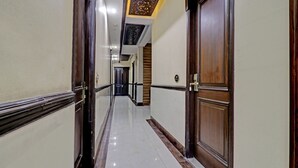 A hallway with wooden doors, a tiled floor, and a ceiling with a decorative light fixture. - Itsy Hotels Hamlets Stay (Noida)