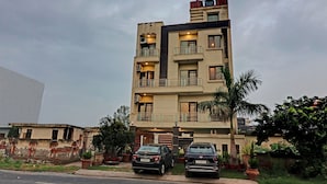 A multi-story residential building with balconies, a gated entrance, and two parked cars. - Itsy Hotels Hamlets Stay (Noida)
