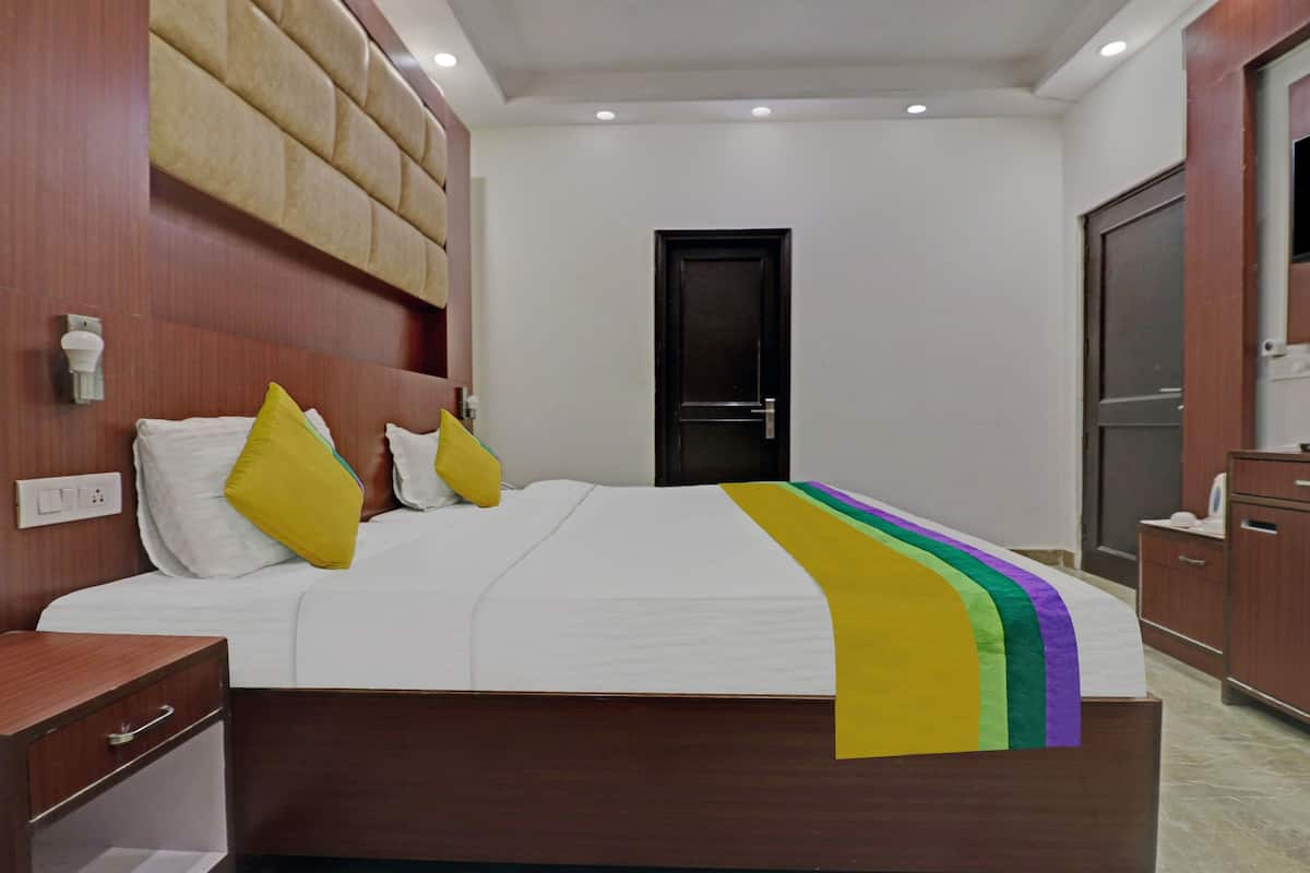 Een hotelkamer met een bed, een houten hoofdbord, een nachtkastje en een kledingkast.
