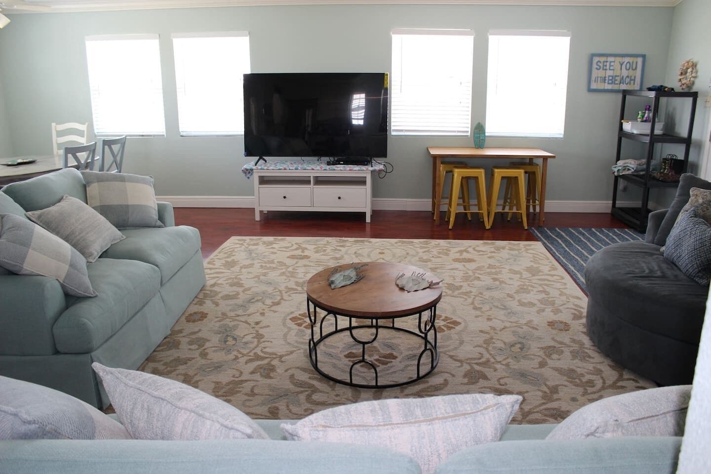 A living room with a sofa, a coffee table, a TV, and a dining area with a table and chairs.