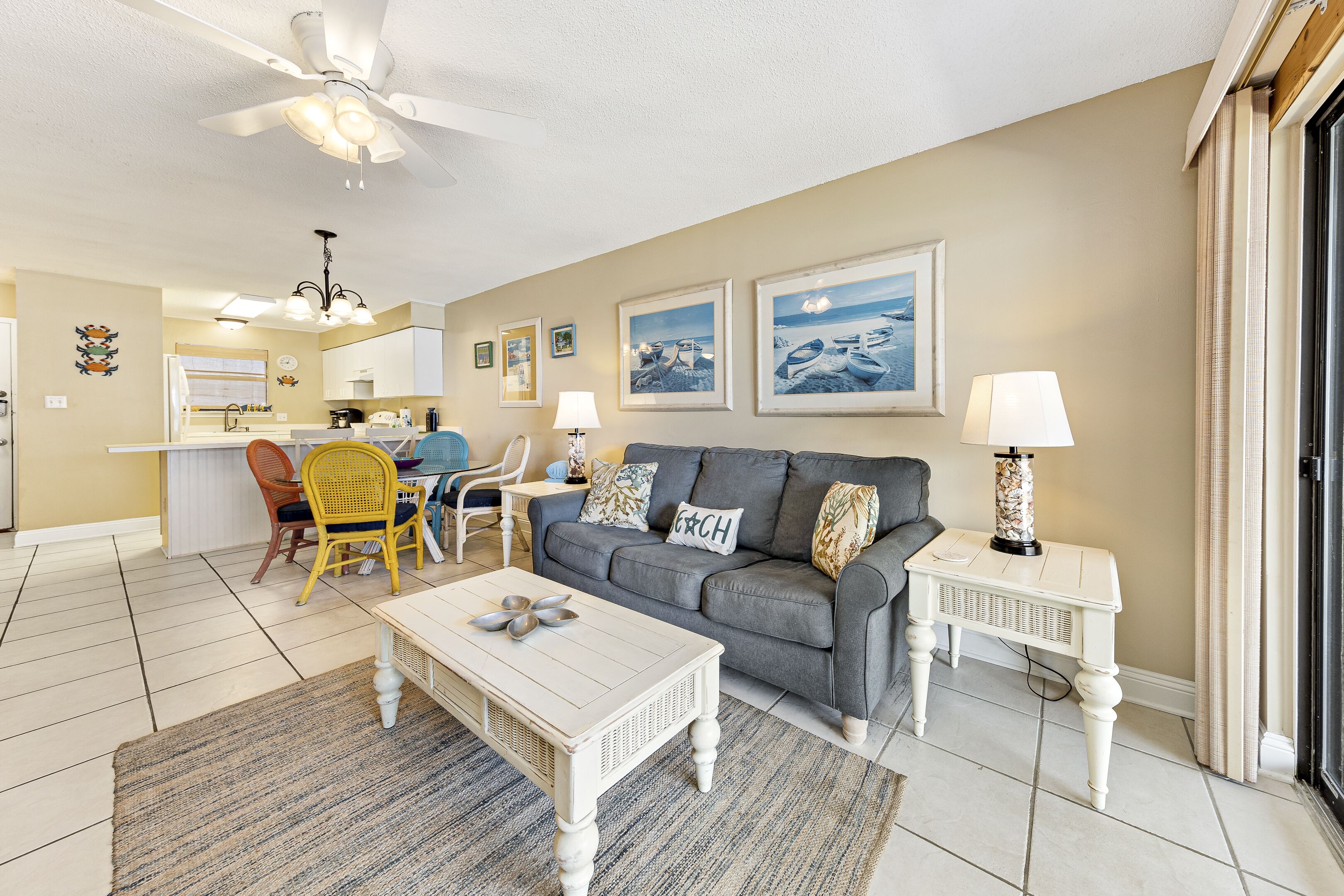 A living room with a grey sofa, white coffee table, and a dining area with a yellow chair.