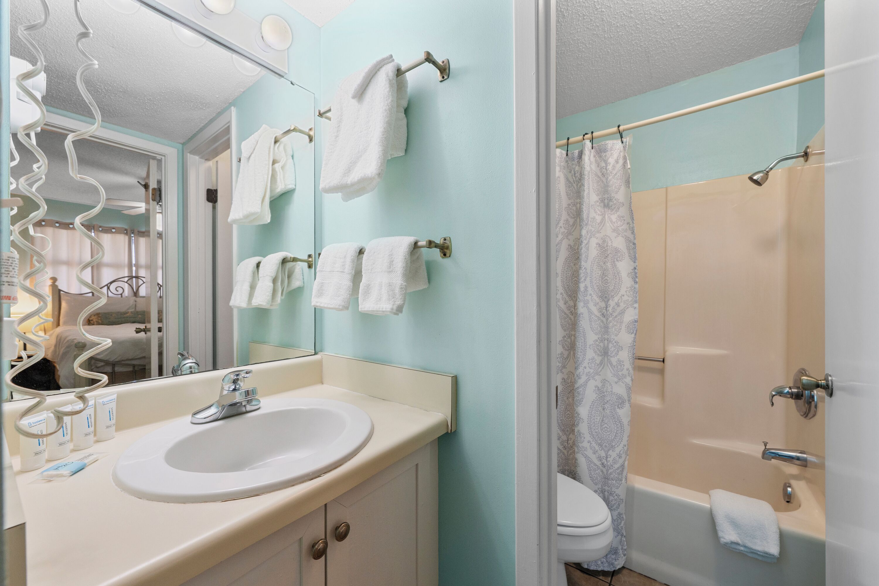 A bathroom with a sink, mirror, and towel rack.