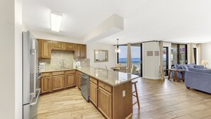 A modern kitchen with wooden cabinets, a built-in island, and a dishwasher. - Seaside Beach & Racquet Condos (Orange Beach)