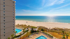 A high-rise hotel with a pool area, beach view, and a clear sky. - Seaside Beach & Racquet Condos (Orange Beach)