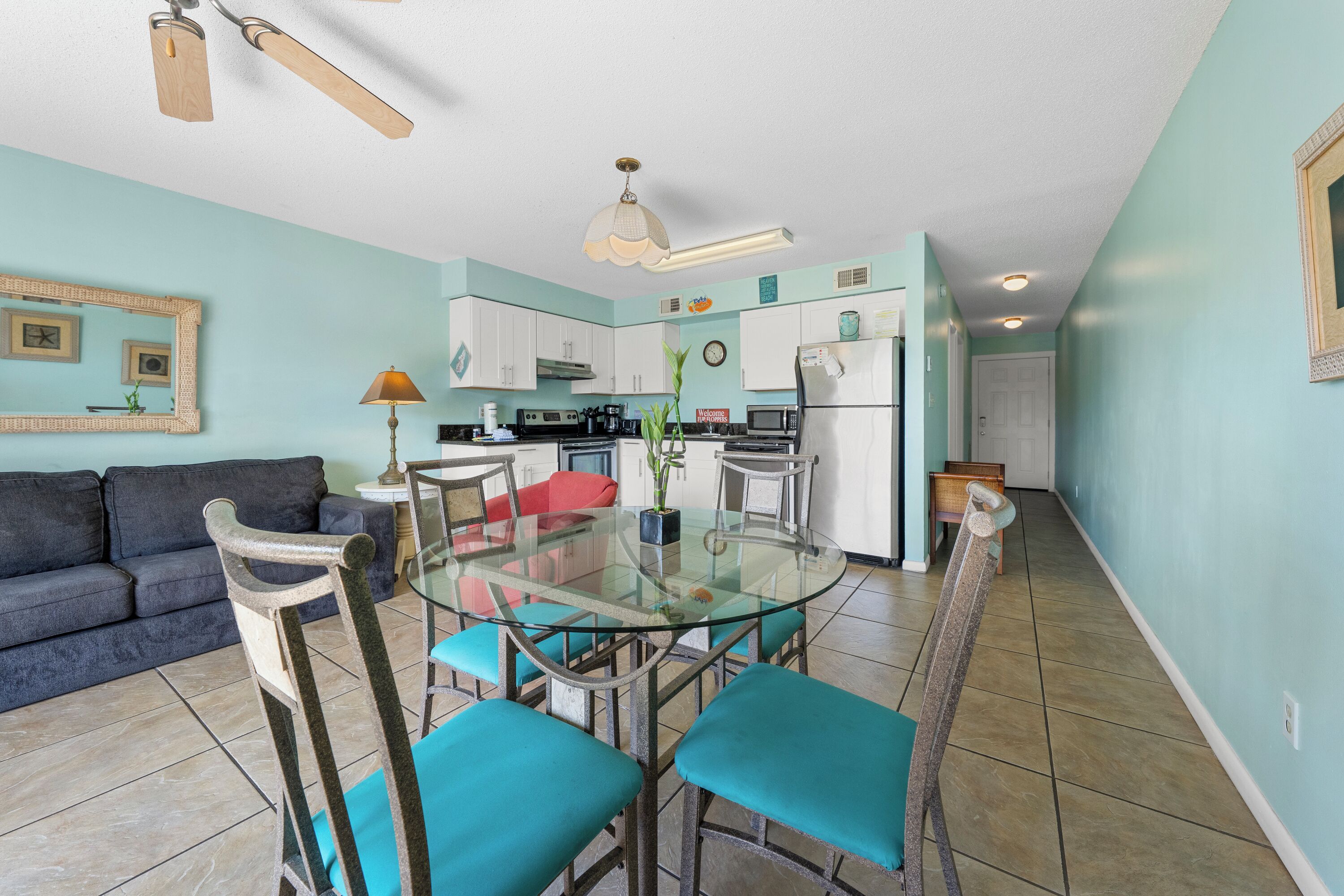 A compact living space with a kitchenette, a dining area with a glass table, and a sofa.