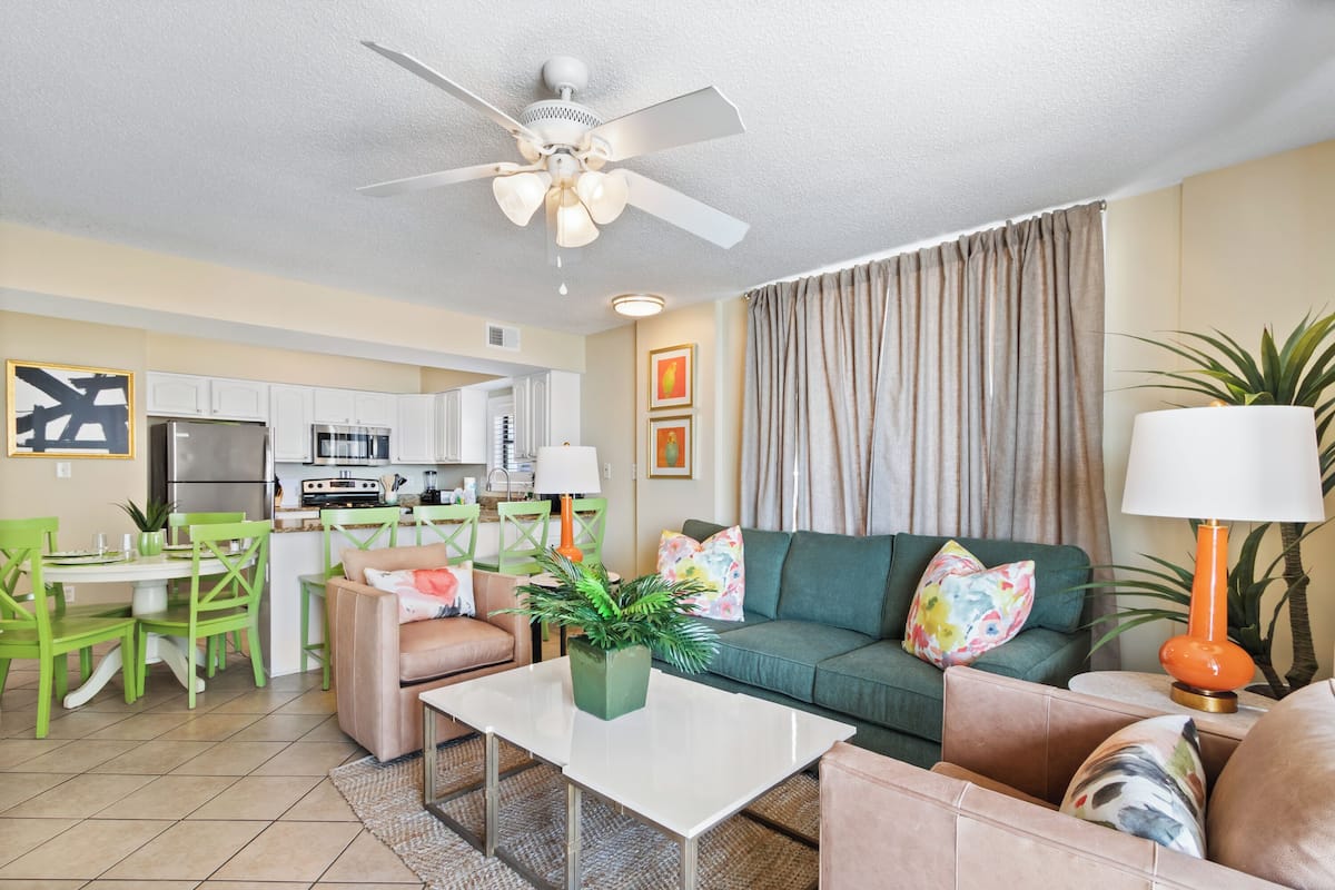 A modern living room with a green sofa, a white coffee table, and a ceiling fan.