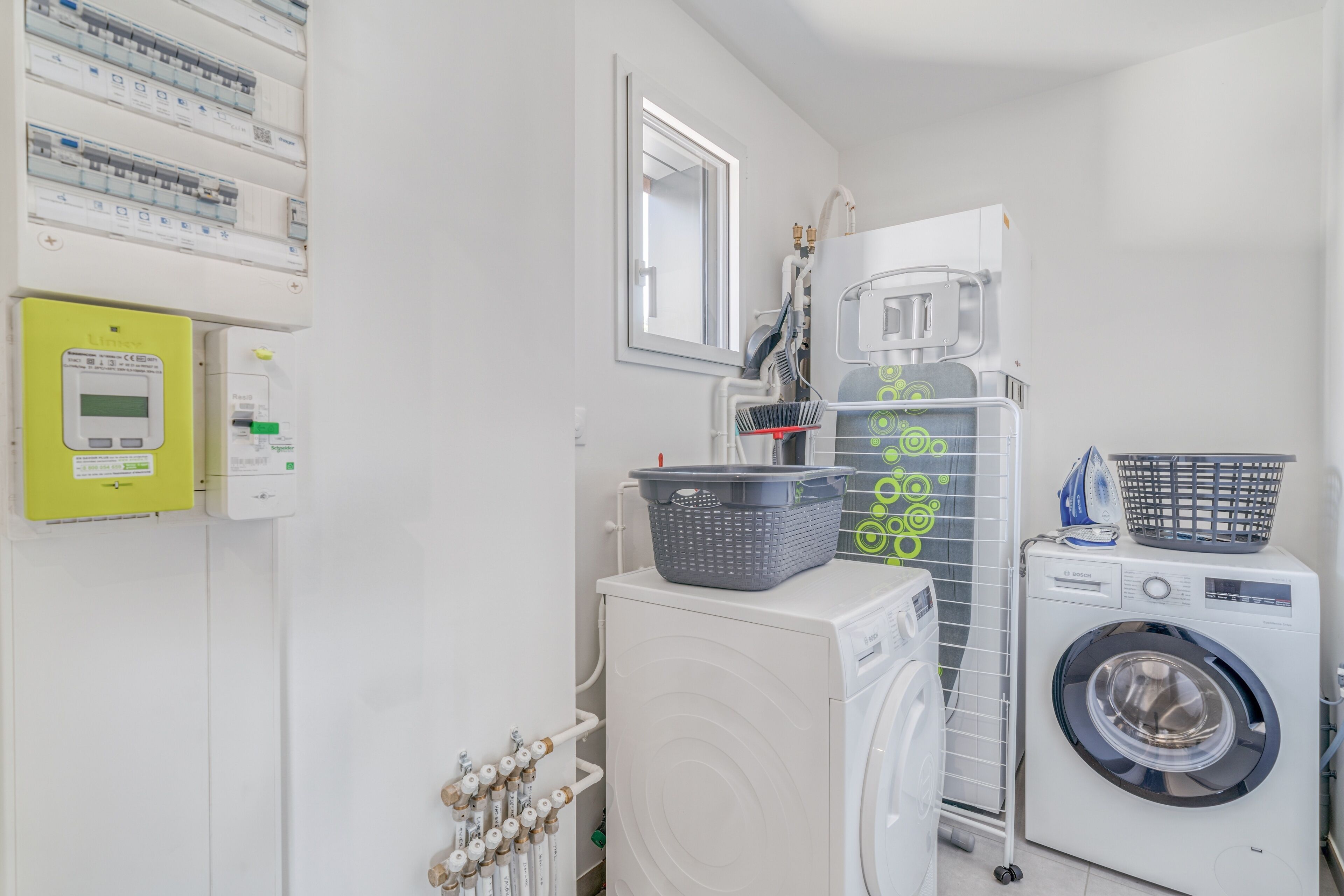 A laundry room with a washing machine, dryer, and stacked laundry baskets.