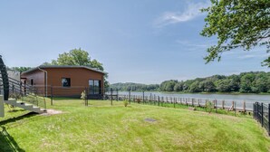 A modern building with a staircase leading to a deck overlooking a river. - Les Roseaux - Vue sur le lac avec jacuzzi (Sanchey)