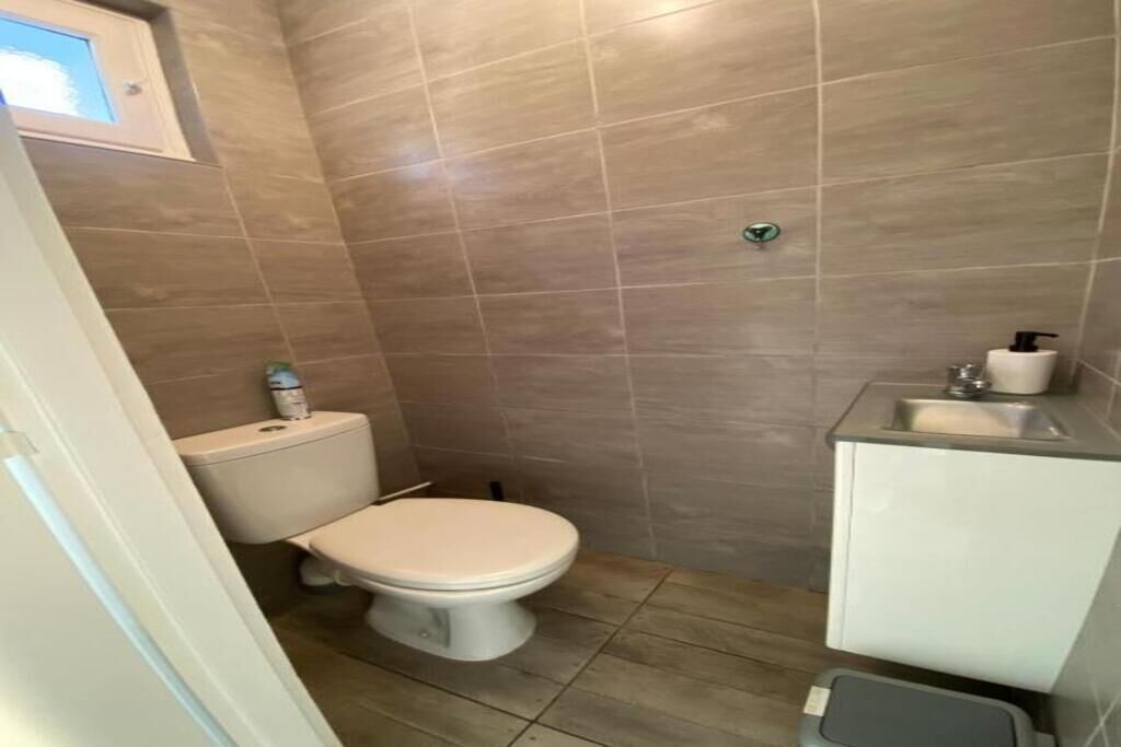 A small bathroom with a toilet, sink, and shower area.