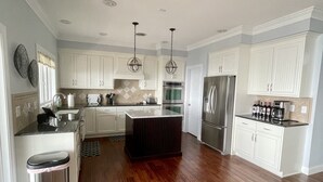 A modern kitchen with white cabinets, stainless steel appliances, and a wooden floor. - Mountain House located on Blue Ridge Parkway  (Galax)