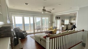 A spacious living area with a wooden floor, a sofa, a dining table, and a balcony with large windows. - Mountain House located on Blue Ridge Parkway  (Galax)