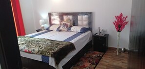 Relax in comfort with a large bed, bedside table, and a floral-patterned rug.