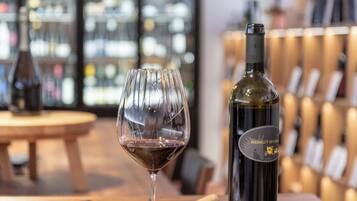 Una copa de vino con vino tinto, una botella de vino y un sacacorchos sobre una mesa de madera.