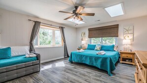 A bedroom with two beds, a ceiling fan, a skylight, and a window with curtains. - Fripp Island/Multi Family Friendly/ Dog Friendly/Spacious 3rd Row home/6 Seater Golf cart incl/-703 Amberjack (Fripp Island)