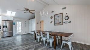 A spacious kitchen with a wooden dining table and white chairs, a ceiling fan, and a chandelier. - Fripp Island/Multi Family Friendly/ Dog Friendly/Spacious 3rd Row home/6 Seater Golf cart incl/-703 Amberjack (Fripp Island)