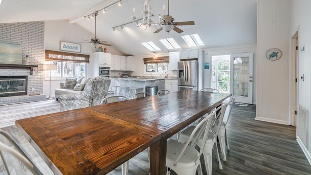 A spacious kitchen with a wooden dining table, white bar stools, and a ceiling fan. - Fripp Island/Multi Family Friendly/ Dog Friendly/Spacious 3rd Row home/6 Seater Golf cart incl/-703 Amberjack (Fripp Island)