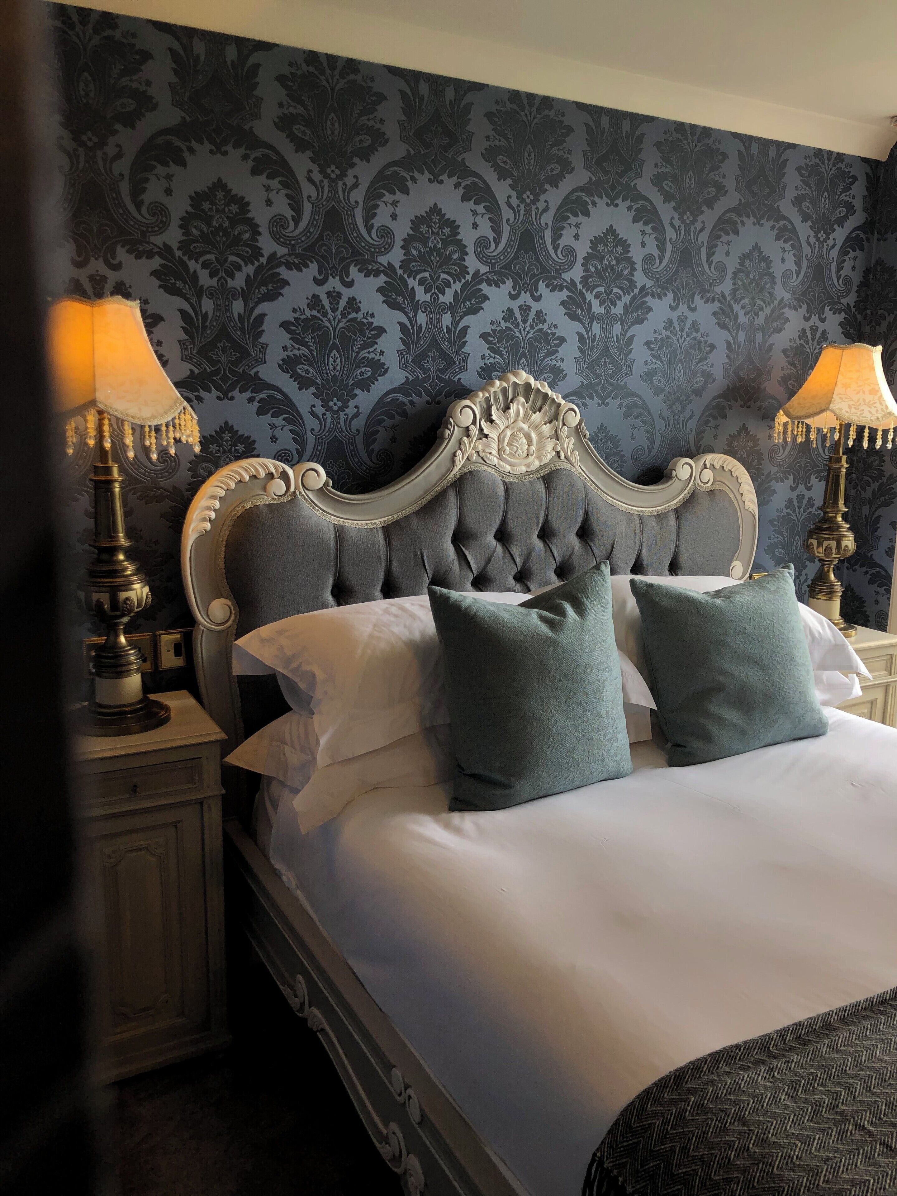 A bed with a tufted headboard, two pillows, and two bedside lamps.