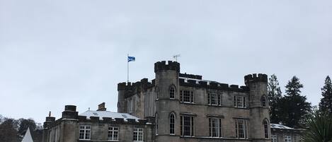 Un bâtiment qui ressemble à un château, avec un drapeau, une tente et de la neige au sol.