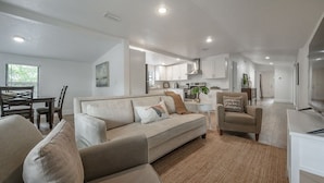 Een moderne woonkamer met een bank, fauteuils en een eethoek.