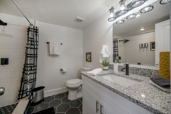 A modern bathroom with a shower, toilet, and sink.