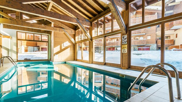 En inomhuspool med träbjälkar och stora fönster.