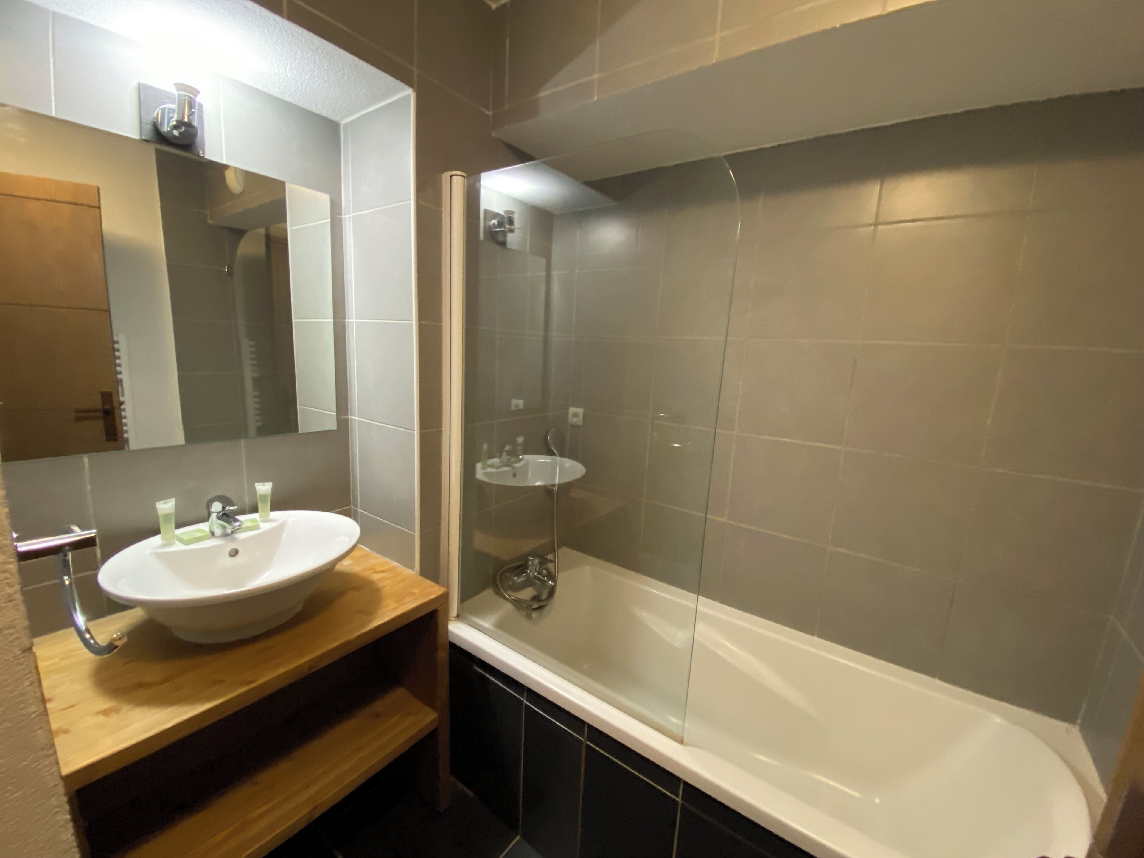A modern bathroom with a white sink, mirror, and glass-enclosed shower.