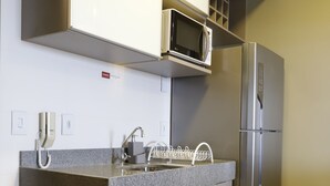 Een moderne keuken met een ingebouwde magnetron, een koelkast van roestvrij staal en een granieten aanrecht.