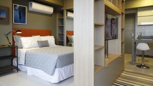 Een moderne slaapkamer met een bed, nachtkastjes, een televisie en ingebouwde planken.