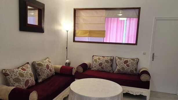 A living room with a sofa set, a round coffee table, and a window with curtains. - La Belle Auvergne 2 / Ground floor F3 - 5 people (Condat)