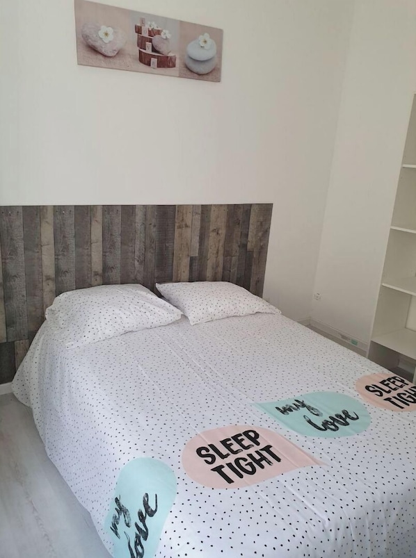 A bedroom with a wooden headboard, a bed with white bedding, and decorative pillows.