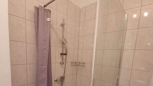 Eine begehbare Dusche mit Glaswänden, Duschkopf und Handbrause.