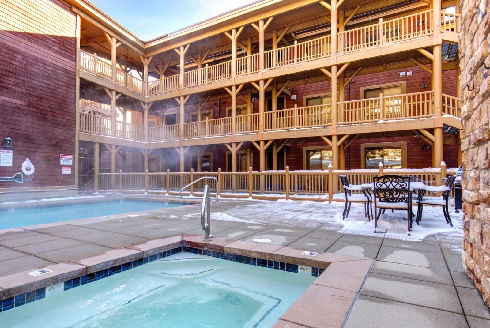 A multi-level wooden building with a hot tub and outdoor seating area.