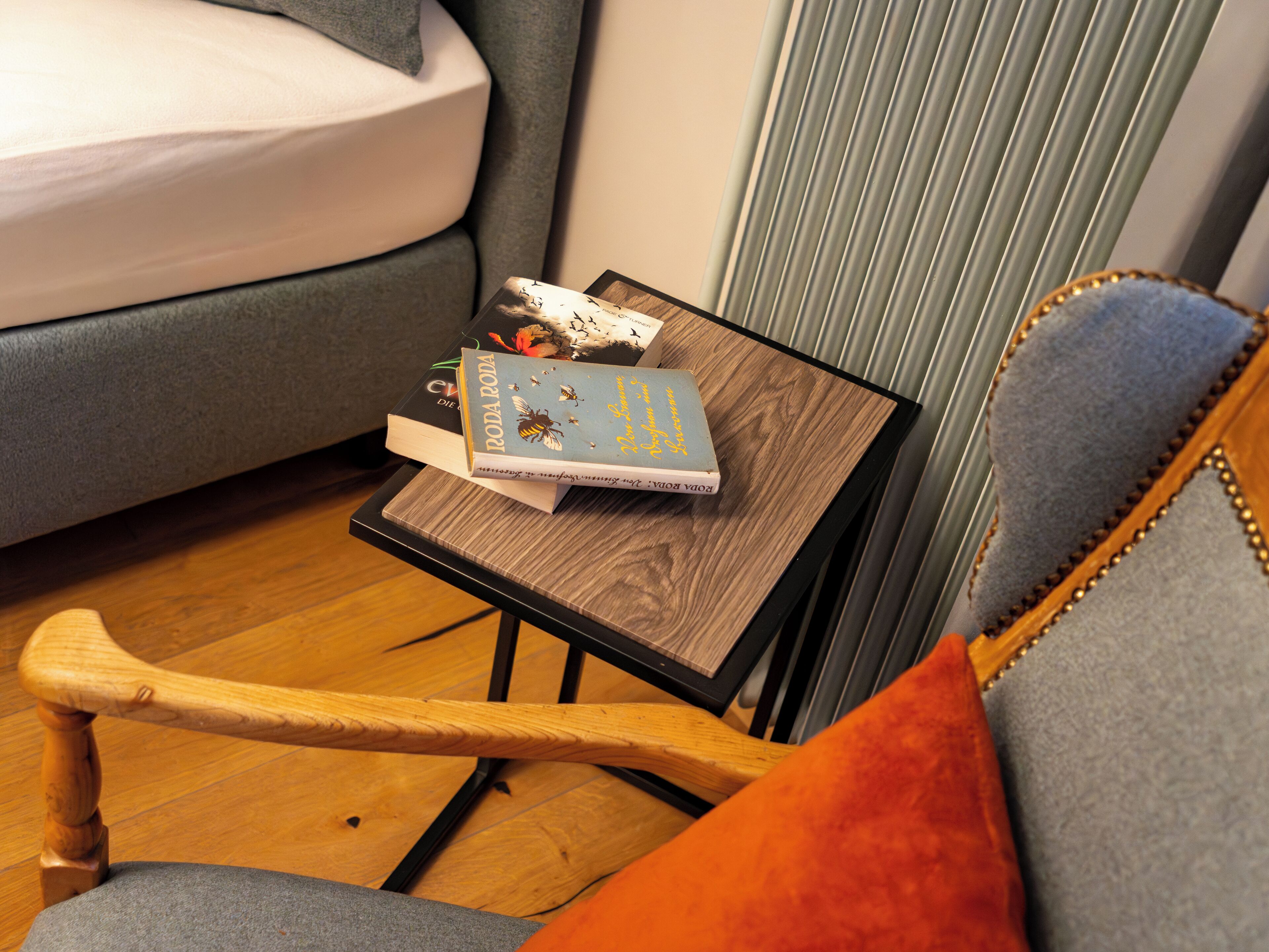 Une petite table en bois sur laquelle sont posés un livre intitulé « Roda Roda » et un autre livre. Une chaise grise est partiellement visible sur la droite.