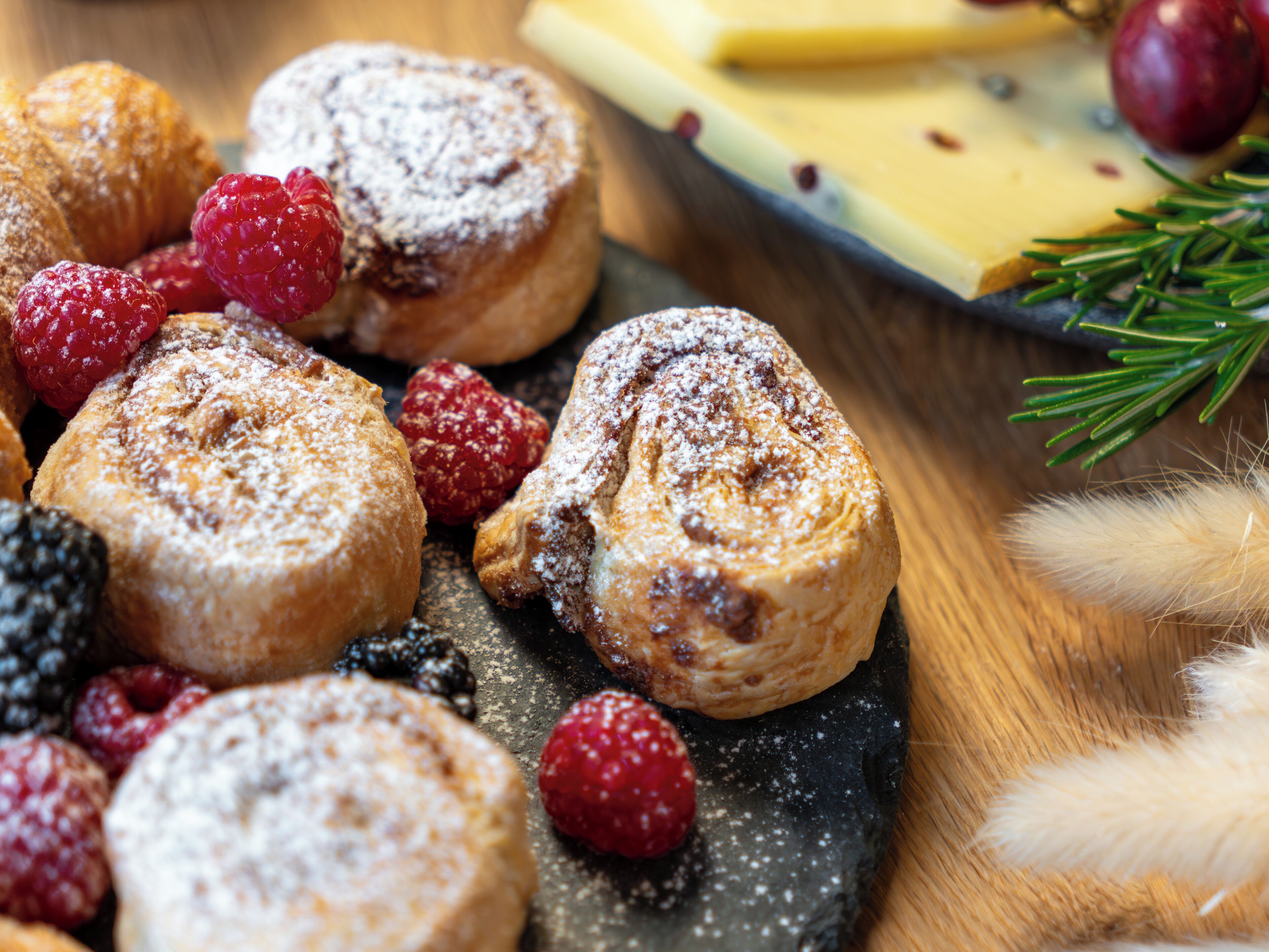 A variety of pastries and berries on a slate serving board.