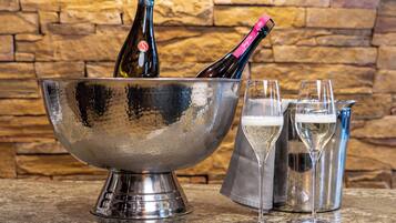 A metallic bowl with bottles and glasses on a granite countertop.
