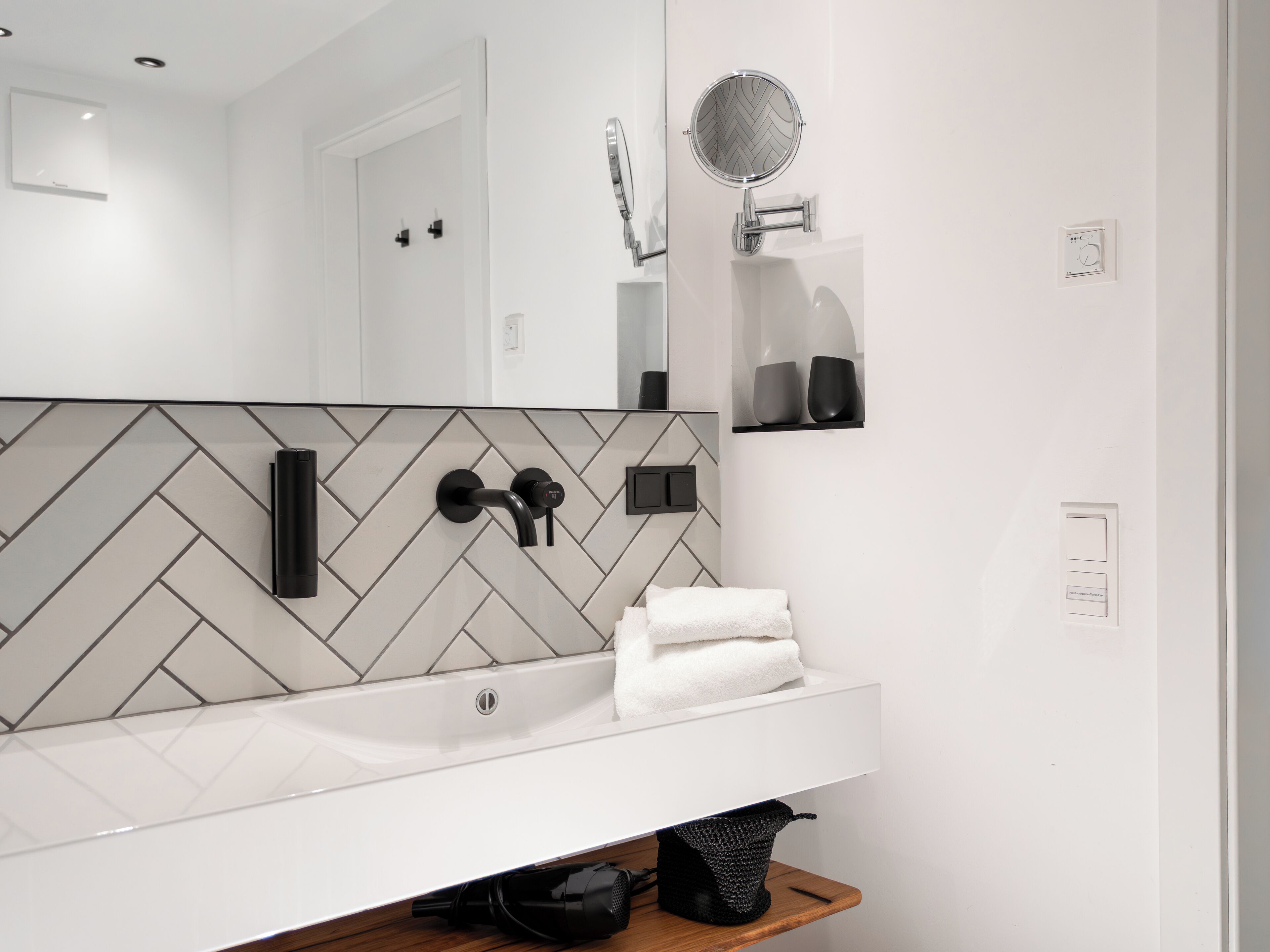 A modern bathroom with a white sink, a mirror, and a towel rack.