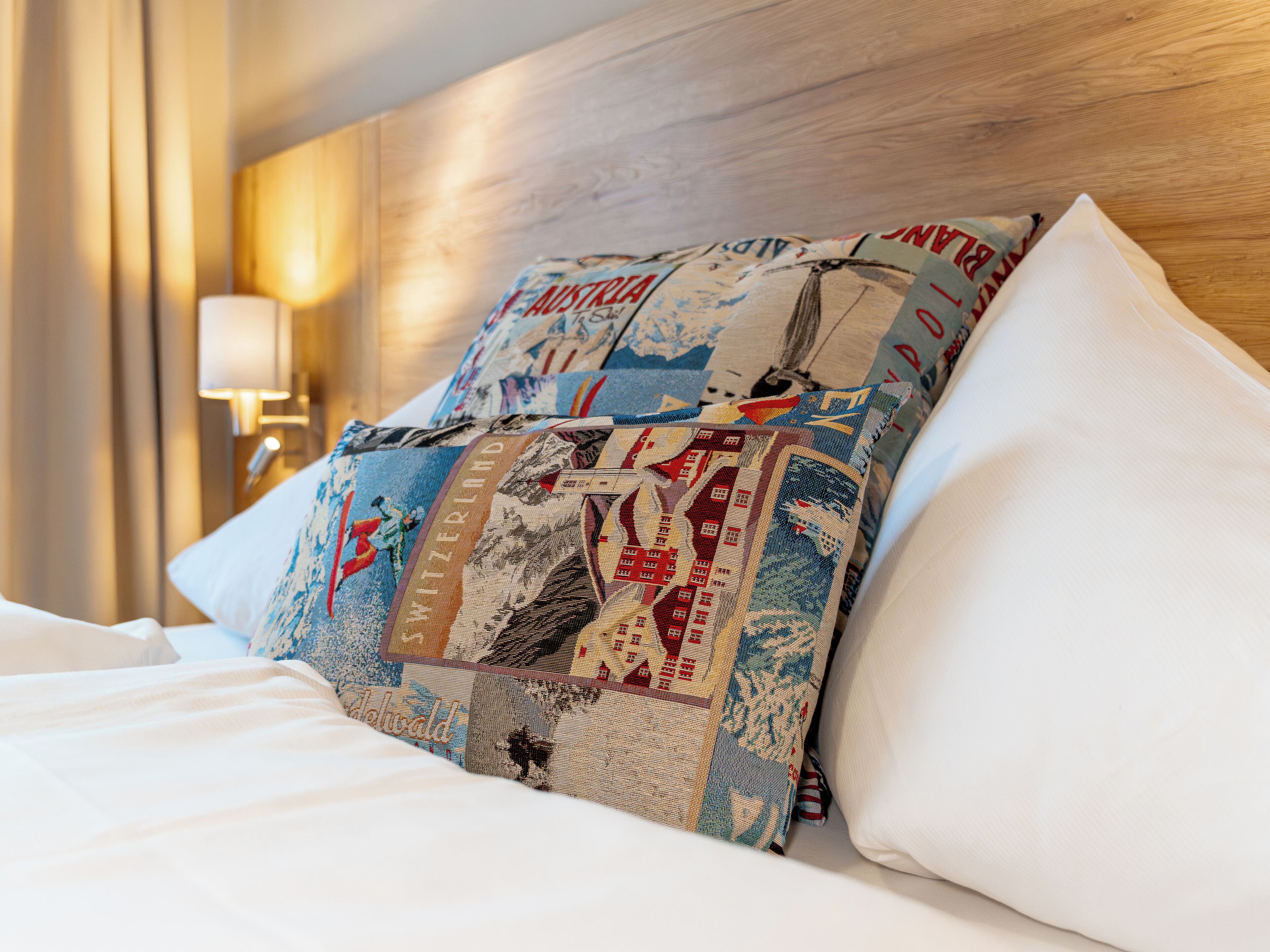 A bed with a quilted pillow featuring a patchwork design, a white pillow, and a wooden headboard.