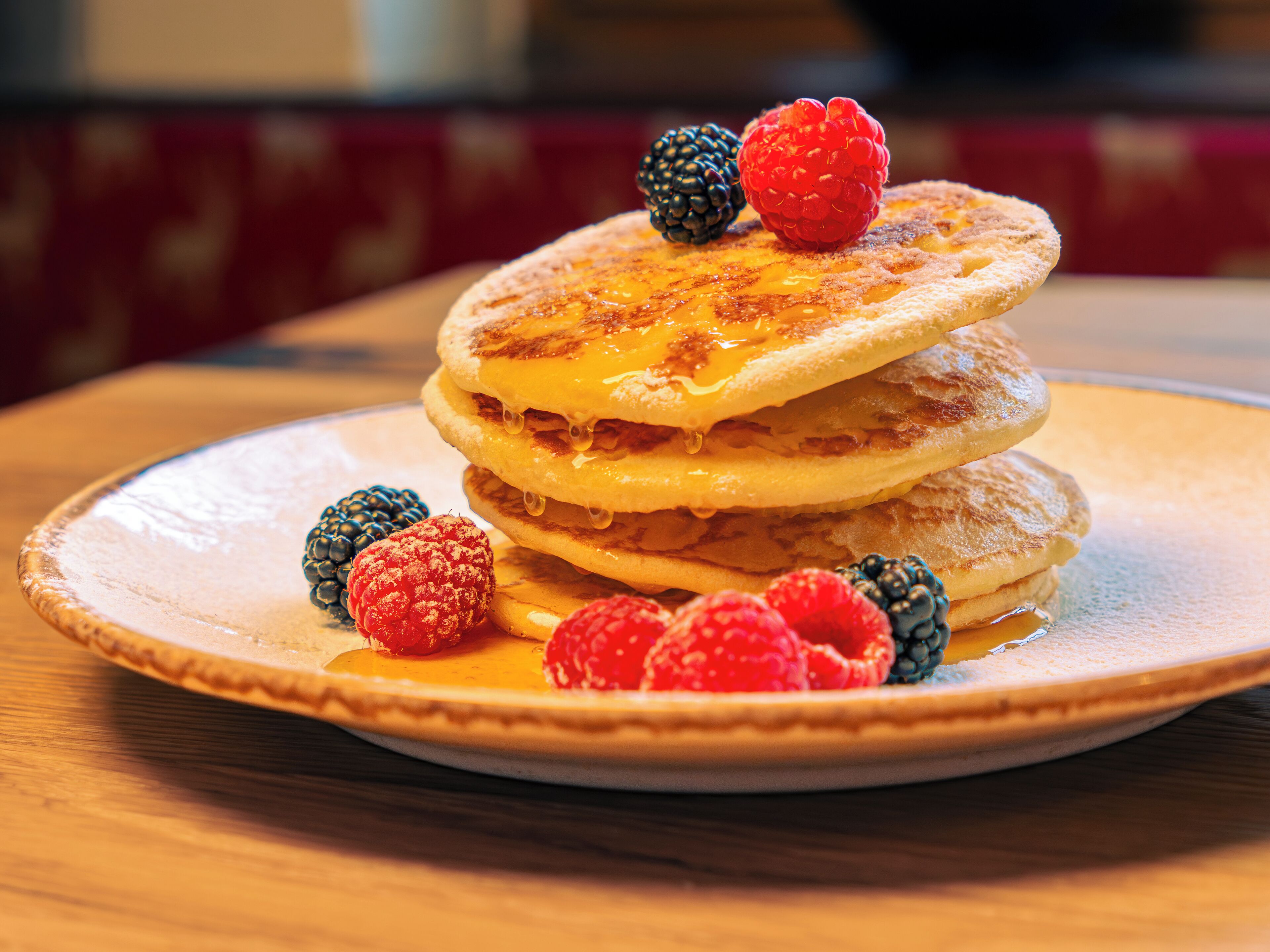 A stack of pancakes with syrup and berries on a plate.