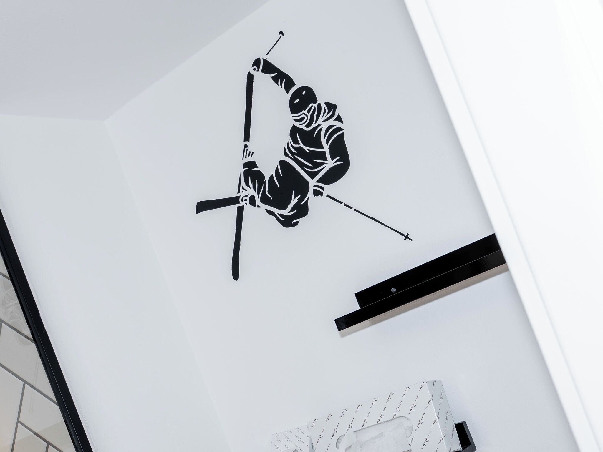 A wall with a black and white wall decal of a skier in a dynamic pose.