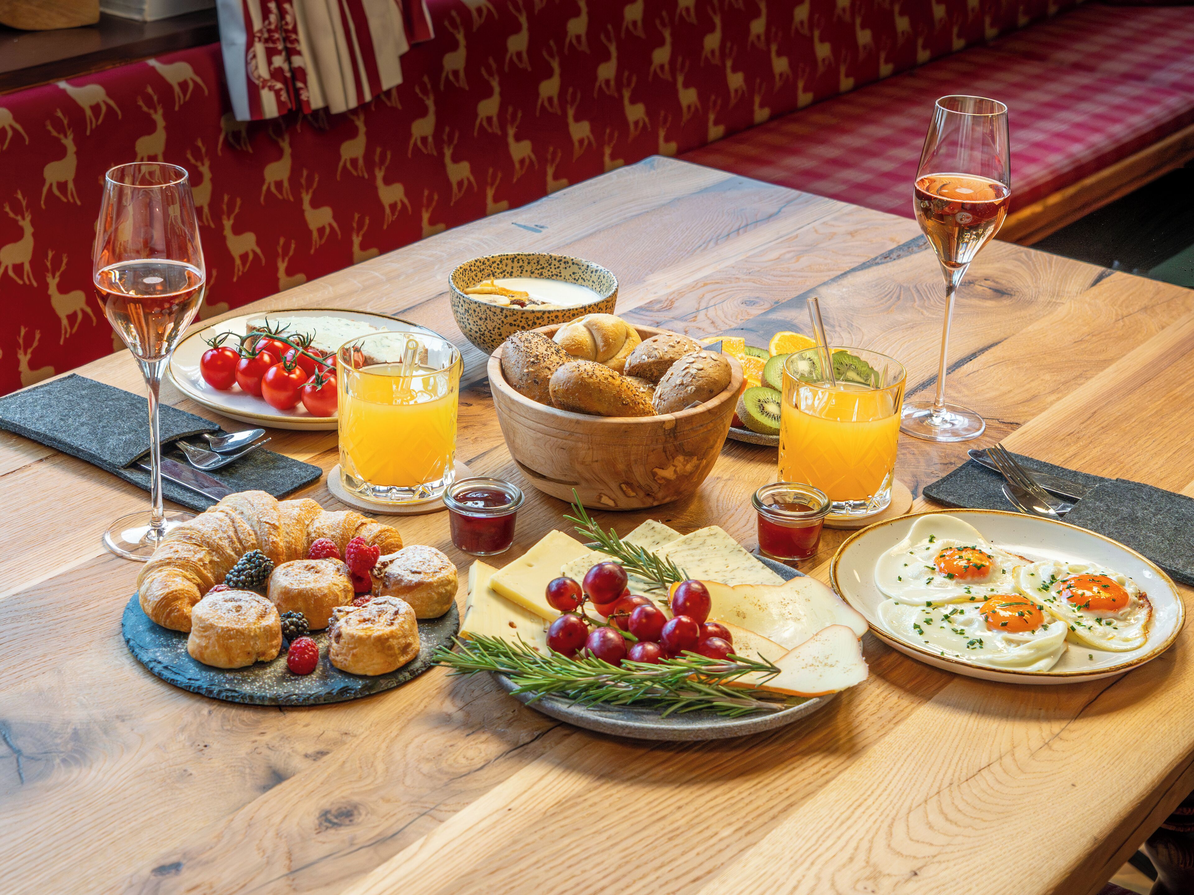 A breakfast table with various foods, drinks, and a cozy seating area in the background.
