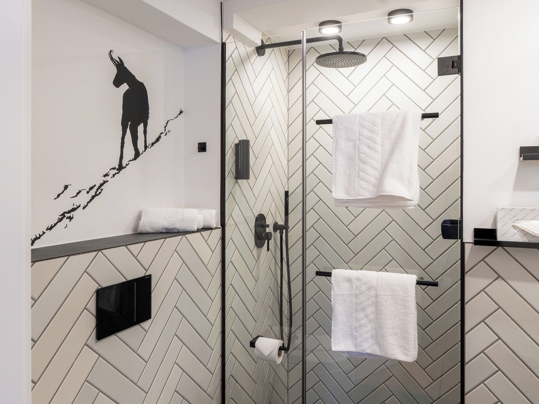 Un baño moderno con un patrón de baldosas en espiga, una ducha con cabezal de ducha tipo lluvia y un perchero de pared.